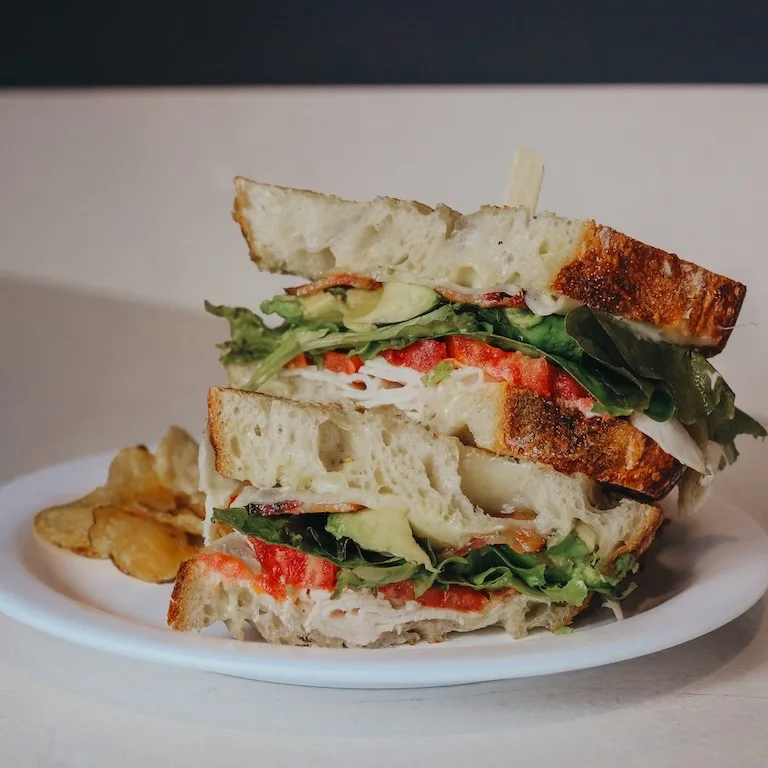 A stacked sandwich on house sourdough with turkey, avocado and tomato